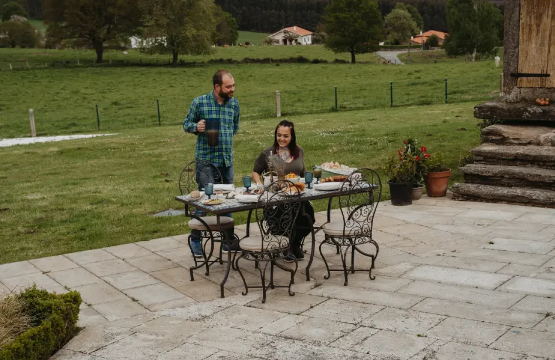 gente comiendo en una mesa en el exterior del jardín del pazo